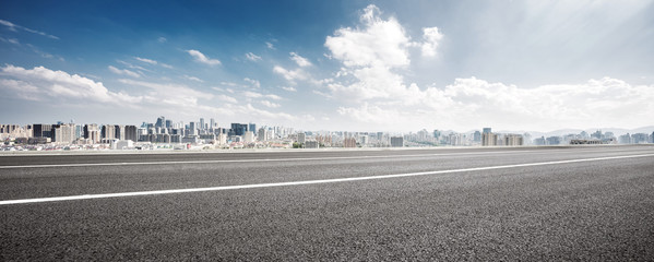 empty road and cityscape of modern city against cloud sky - obrazy, fototapety, plakaty