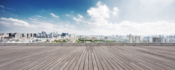 empty wood floor and cityscape of modern city against cloud sky