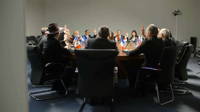 Representatives or delegates from different countries vote for new law at the round table during an important political debates