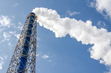 Smokestack and steam on blue sky background