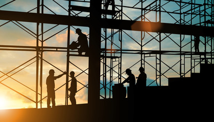 Silhouette construction industry team safely to work load concrete building according to set goal over blurred background sunset pastel for industry background.