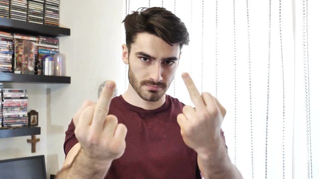 Handsome young man showing middle fingers gesturing Screw You