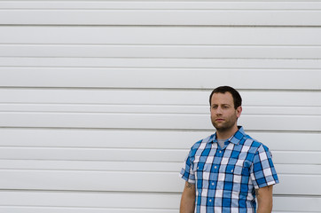 Man alone against a white wall looking at the camera.