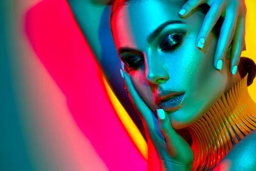Fotobehang Mannequin vrouw in kleurrijke felle lichten met trendy make-up en manicure poseren in studio © Subbotina Anna
