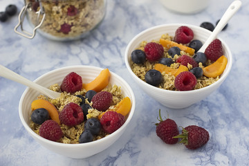 Bowls of  granola  with  fresh fruit on marble table.