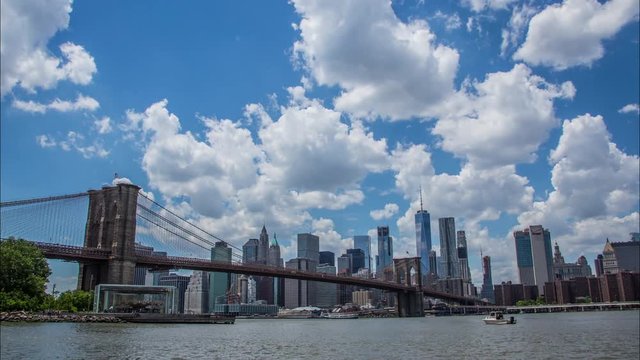 Magnificent time lapse wide angle shot of Brooklyn Bridge and Manhattan skyscrapers against blue sky and clouds