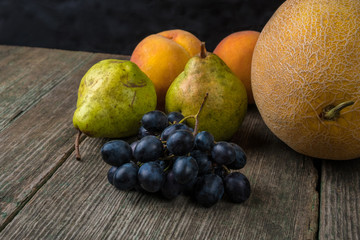 Melon, grapes, peach and Pear on old wooden table.