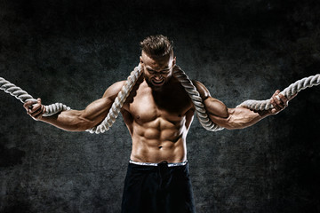 Muscular man with rope. Photo of man with perfect body after training. Fashion style