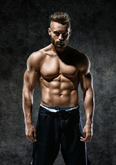 Sporty man with perfect body after training on dark background. Strength and motivation