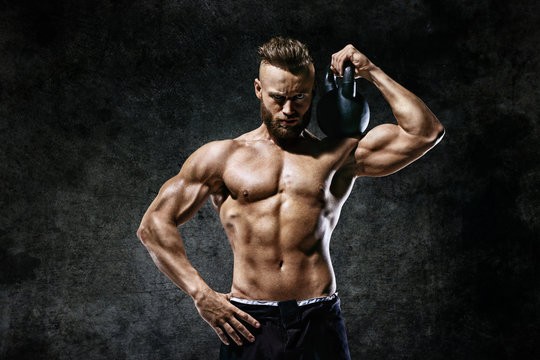 Athletic man working out with a kettlebell. Photo of man on dark background. Strength and motivation