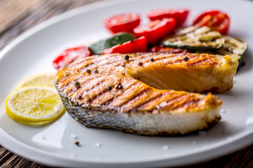 Salmon. Grilled salmon steak with tomatoes and zucchini on white plate