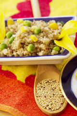 Quinoa salad on rustic plate and wooden spoon with raw quinoa