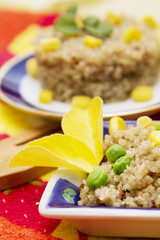 Quinoa salad on rustic plate and wooden spoon with raw quinoa