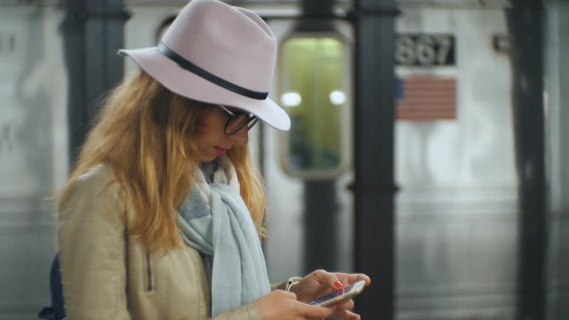 Slow motion shot of blond girl looking at her mobile phone in New York City metro station