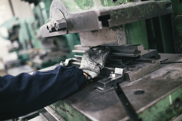 Metallurgy heavy industry. Factory for production of heavy pellet stoves and boilers. Worker hands close up. Extremely dark conditions and visible noise.