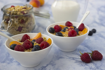 Bowls of  granola  with  fresh fruit on marble table.