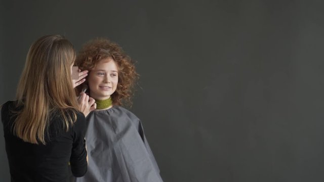 make up artist doing professional make up of young woman