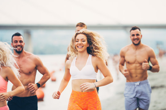 Group of young attractive people fitness workout. They having fun and running at beach.