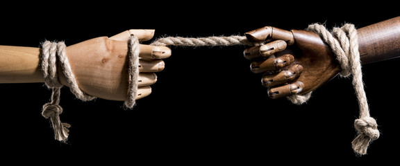 Teamwork concept. Black and white hands pulling the rope. Isolated on black background. With copy...