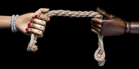 Concept romantic relationship. Hands of female and man pulling the rope. Isolated on black background. With copy space text. Studio Shot.