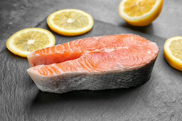 Fresh salmon steak with slices of lemon on slate plate