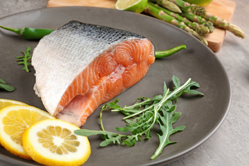 Fresh salmon fillet with arugula and lemon on plate