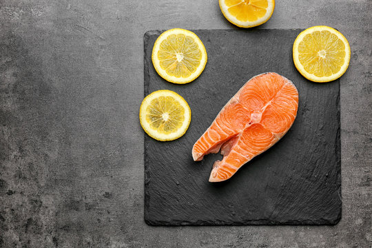 Fresh salmon steak with slices of lemon on slate plate