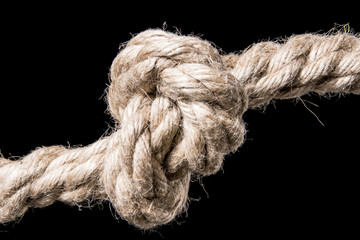 Rope knot isolated on a black background. Symbol for trust and faith and a metaphor for strength or stress. With copy space text. Studio Shot.