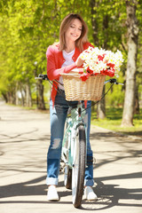 Young beautiful girl with bicycle in park on sunny day