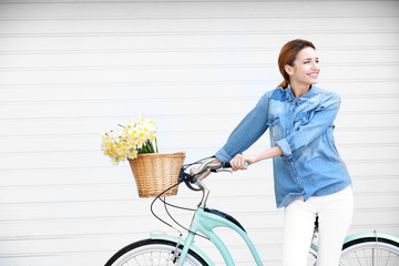 Young beautiful girl with bicycle and basket of flowers, outdoors