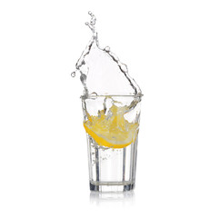 Fresh slice of lemon falling into glass with water on white background