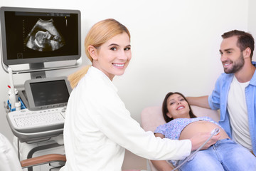 Obraz premium Young pregnant couple undergoing ultrasound scan in clinic