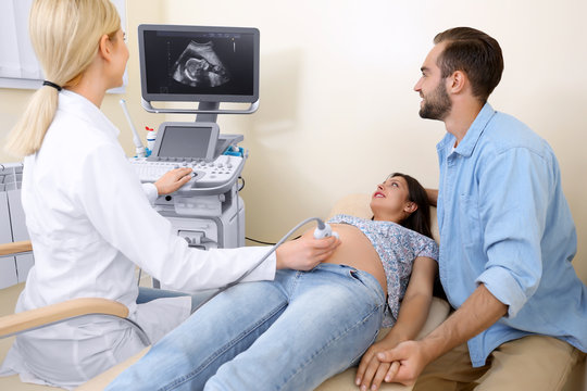 Young pregnant couple undergoing ultrasound scan in clinic
