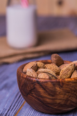 Almond milk in bottles with almond nuts on wooden background