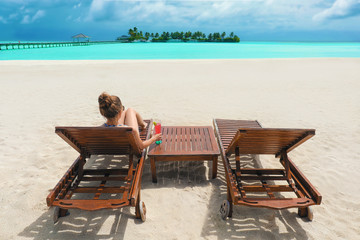 Beautiful young woman resting on sun lounger at sea resort