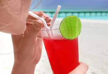 Young woman with cocktail on sea beach, closeup