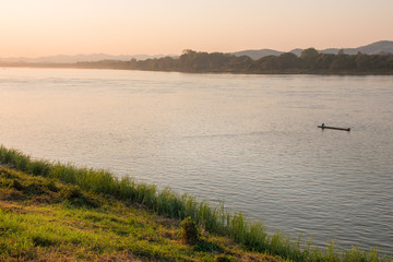 Rural river landscape with fisherman on wooden boat in river