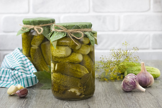Pickled cucumbers in glass jar on a gray wooden table
