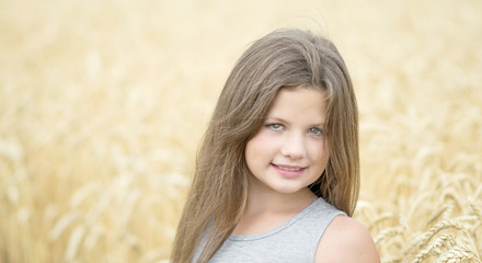 A beautiful smiling little girl. A wheat field background