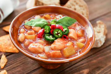 Bowl with delicious turkey chili on wooden table