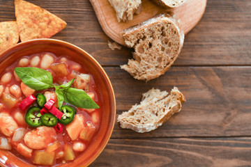 Composition with delicious turkey chili in bowl on wooden table