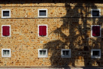 Natural stone facade of a rural house with a tree shadow on it