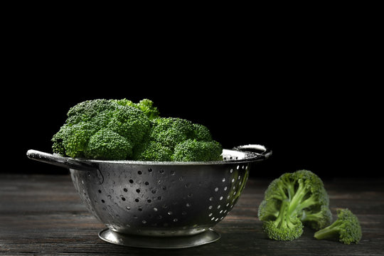 Colander with fresh green broccoli on table