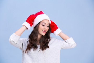 Beautiful emotional woman in Christmas hat and red winter gloves on color background