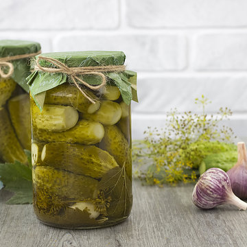 Pickled cucumbers in glass jar on a gray wooden table