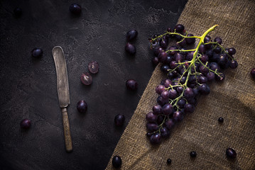 Blue grapes on concrete background with knife