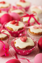 Easter cupcakes with white icing decorated with pink candy and ribbons.