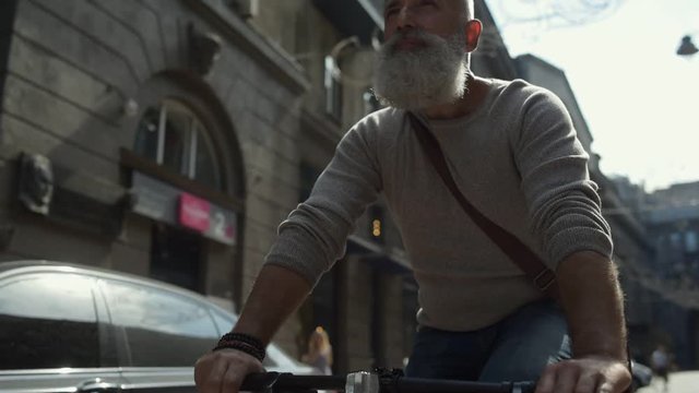 Joyful Mature Guy Riding Bicycle In Downtown