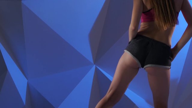 Dance twerk in the performance of professional dancer in shorts on a blue graphic background. Close up