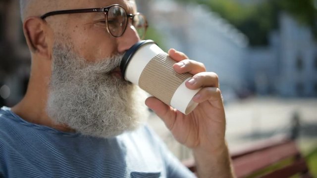 Senior gentleman wearing glasses drinking coffee outdoors